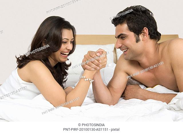 Couple arm wrestling on the bed