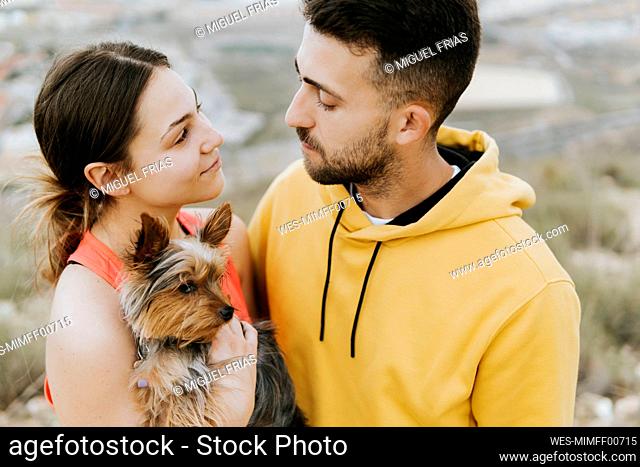 Young man looking at woman holding dog in hand