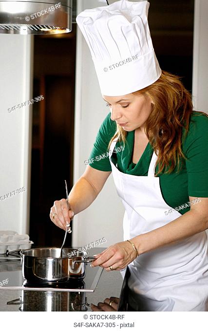 Woman wearing apron and chef's hat cooking in kitchen