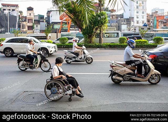 PRODUCTION - 26 September 2022, Vietnam, Hanoi: Sidewalks in Vietnam are almost always inaccessible to wheelchair users, so Hieu Luu (front) has to drive her...
