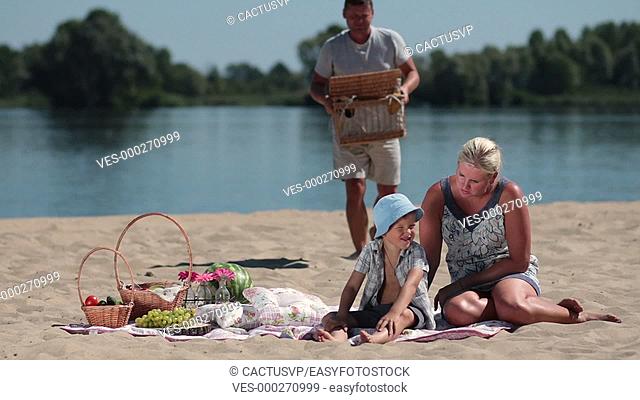 Happy family having picnic on the beach