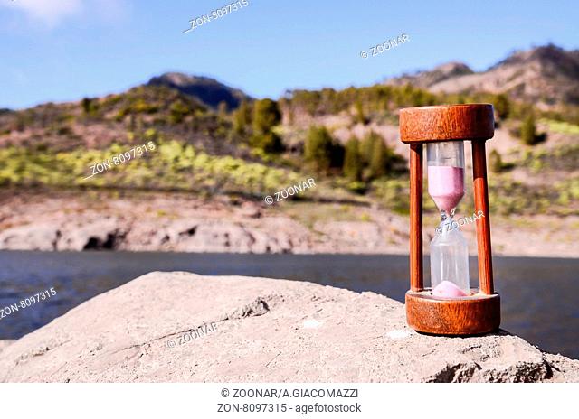 Time Concept White Sand Hourglass on the Volcanic Rocks