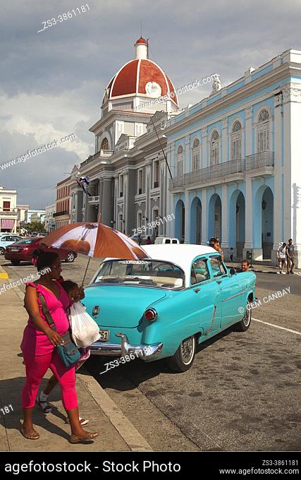 Cuban woman with an umbrella in front of the Palacio De Gobierno-Government Palace at Parque Jose Marti in Plaza de Armas Square, Cienfuegos, Cuba, West Indies