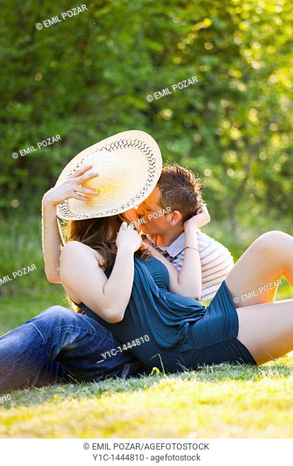 Shy young couple kissing on the grass