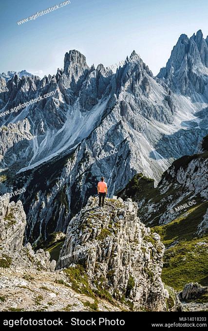 man hiker standing and admiring stunning beauty of impressive jagged peaks of cadini di misurina mountain group in dolomites, italy