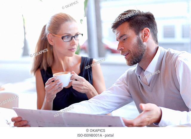 Mature man and woman, sitting outside cafe, having discussion