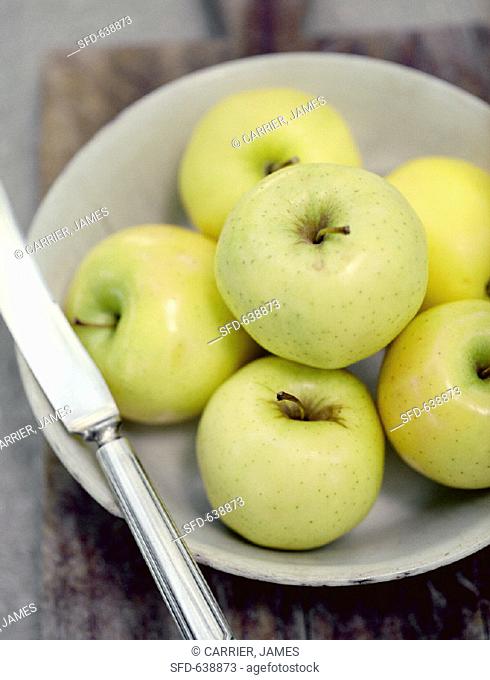 A Bowl of Golden Delicious Apples with Knife