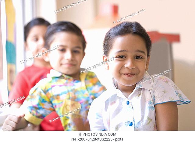 Portrait of a schoolgirl grinning with two schoolboys behind her