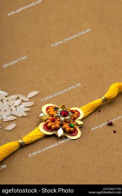 Raksha Bandhan background with an elegant Rakhi, Rice Grains and Kumkum. A traditional Indian wrist band which is a symbol of love between Brothers and Sisters