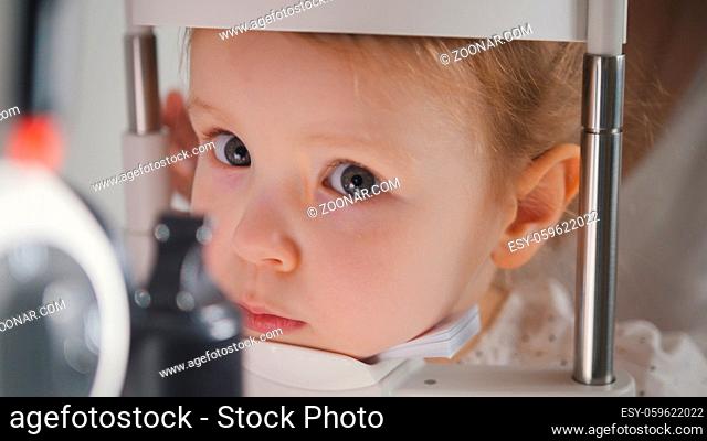Cute child in ophthalmology clinic - optometrist diagnosis little blonde girl, close up