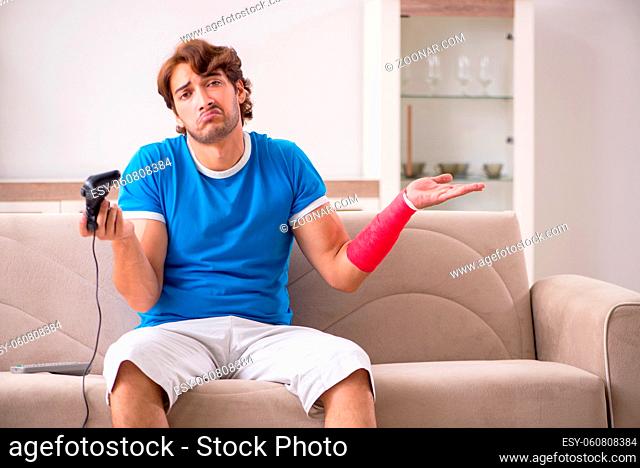 Young man with injured arm sitting on the sofa