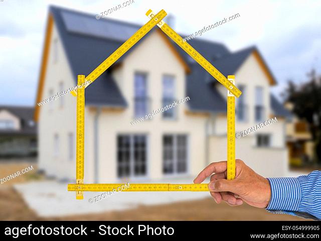 yardstick folded in form of an house in hand of an agent