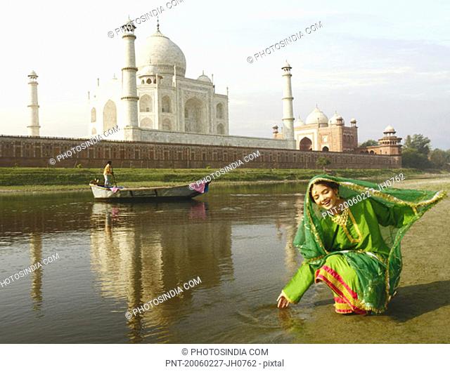 Young woman crouching on the riverbank, Taj Mahal, Agra, Uttar Pradesh, India