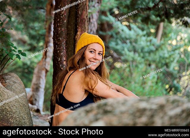 Smiling woman sitting in forest at La Pedriza, Madrid, Spain