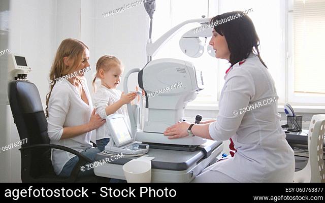 Doctor optometrist in clinic checking little girl's vision - children's ophthalmology, wide angle