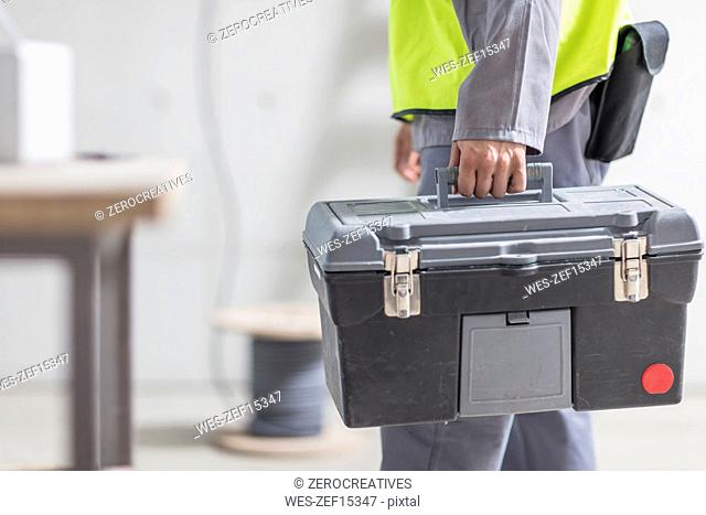 Close-up of construction worker carrying tool box