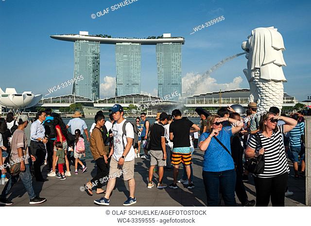 Singapore, Republic of Singapore, Asia - Tourists visit Merlion Park along the Singapore River with the Marina Bay Sands Hotel in the backdrop