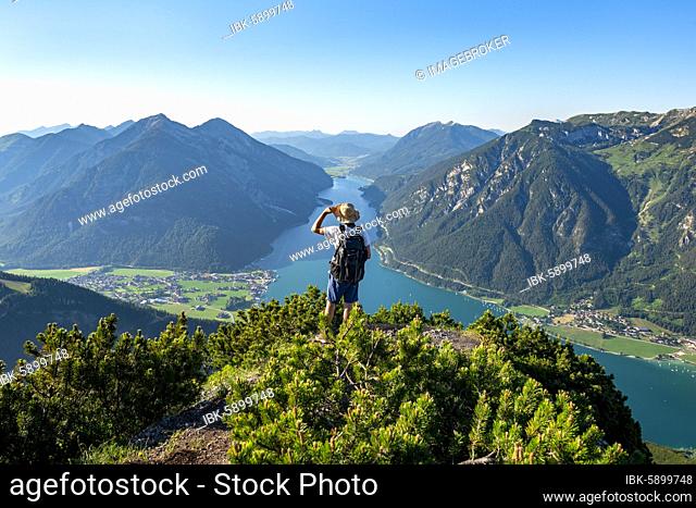 Hiker looks into the distance, view from Bärenkopf to Achensee, left Seekarspitze and Seebergspitze, right Rofangebirge, Karwendel, Achensee, Tyrol, Austria