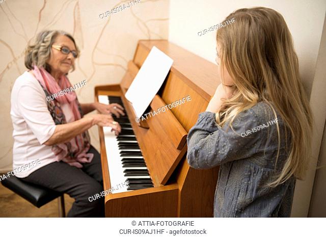 Granddaughter watching grandmother playing piano