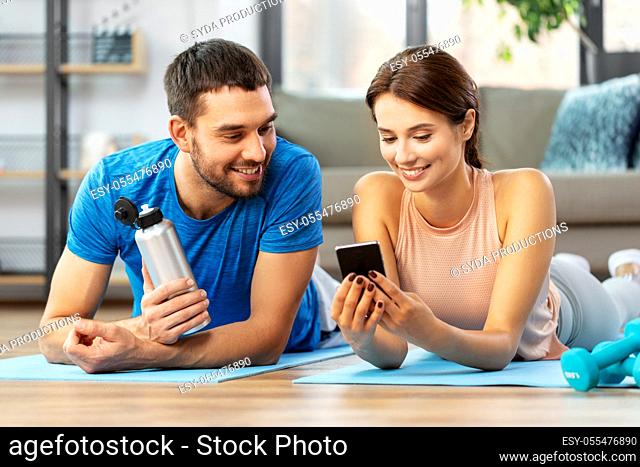 happy couple with smartphone after sports at home
