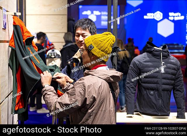 28 November 2023, Bavaria, Munich: Visitors look at sportswear during the ISPO sporting goods trade fair at Messe München