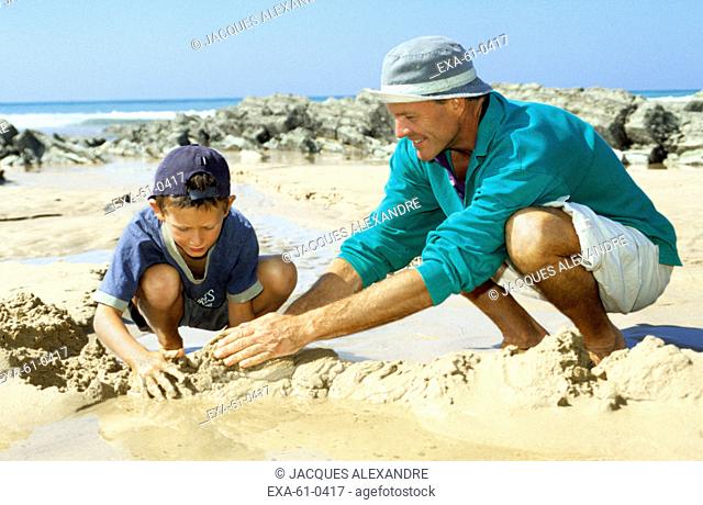 Father and son playing in sand at beach