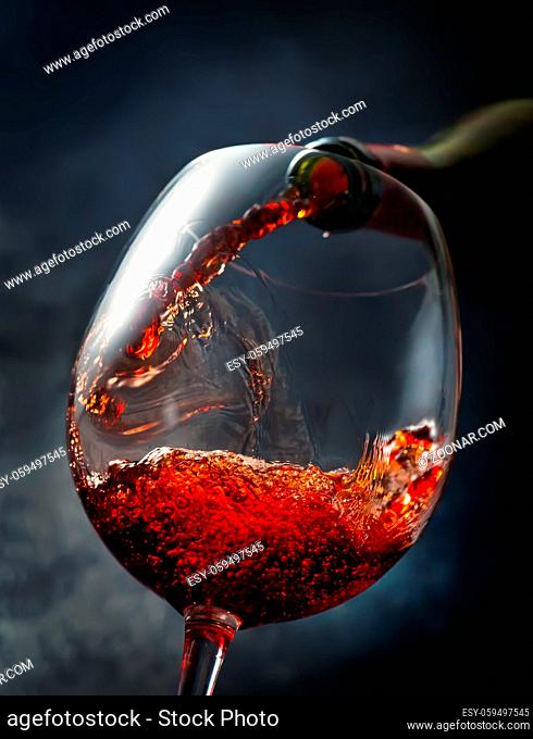 Wine pouring from bottle into wineglass on smoky background