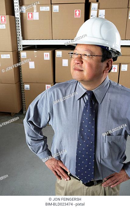 Middle-aged Asian businessman wearing hard hat in warehouse