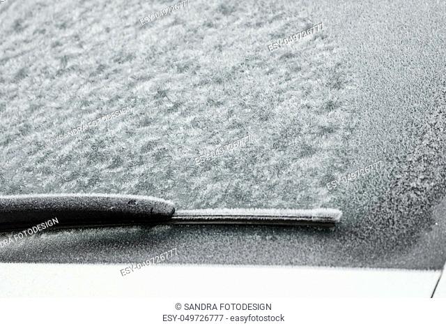 A windshield wiper of a car completely iced in winter