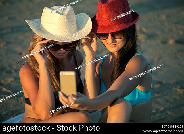 Beautiful girls in bikinis on the beach doing selfie