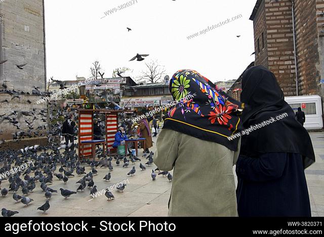 Traveling around Istanbul. Women walking with their heads covered by a hijab near the New Mosque surrounded by pigeons