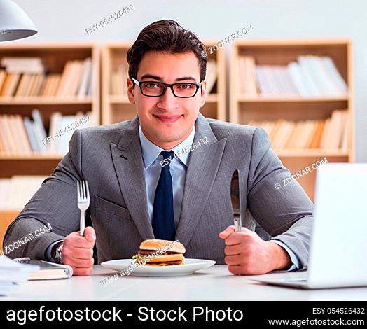 The hungry funny businessman eating junk food sandwich