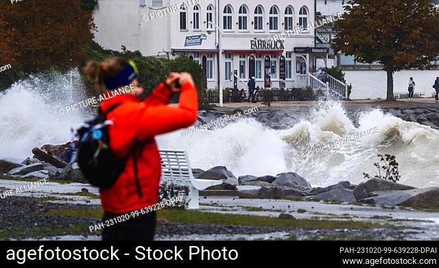 20 October 2023, Mecklenburg-Western Pomerania, Sassnitz: A woman takes a picture of the high waves on the beach promenade during a severe storm depression