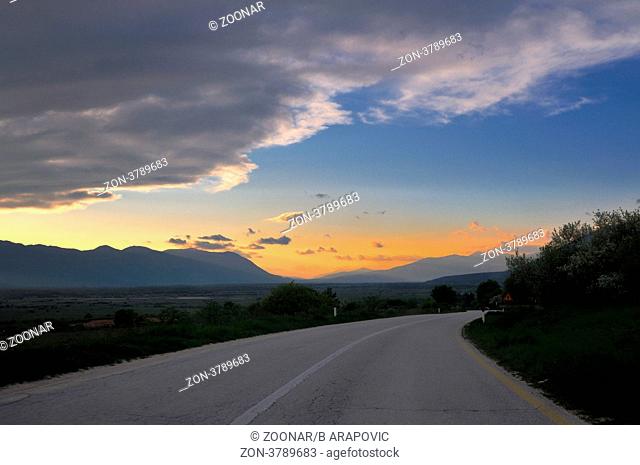landscape in nature and countryroad adventure with beautiful sunset and dramatic clouds and sky
