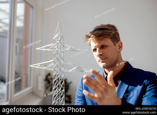 Businessman analyzing electricity pylon model in office