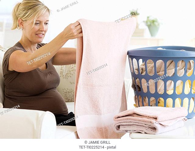 Pregnant woman folding laundry
