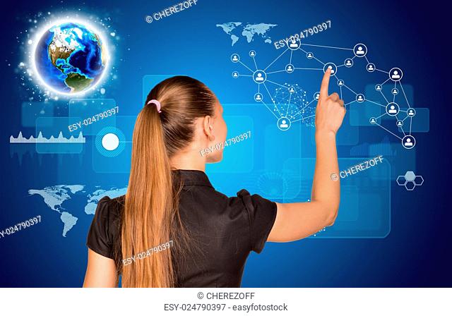 Beautiful businesswoman pointing finger on network with people icons. Earth and graphs in background. Elements of this image furnished by NASA