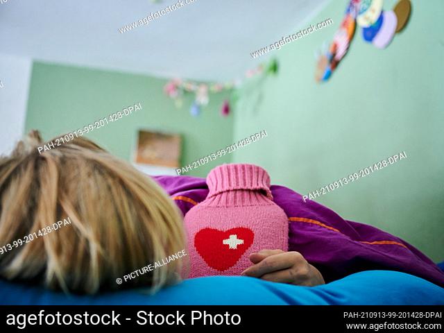 ILLUSTRATION - 11 September 2021, Berlin: A child lies in bed with a hot water bottle. Photo: Annette Riedl/dpa. - Berlin/Berlin/Germany