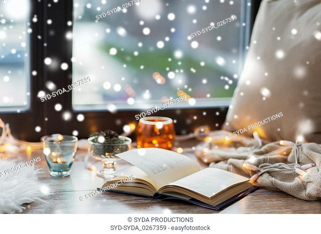 book, garland lights and candles on window sill