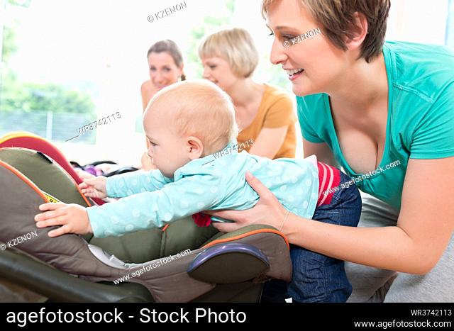 Moms and babies in mother and child course practicing with baby seats