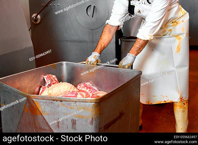 Worker operating machinery for production of sausages in a meat processing plant. High quality photo