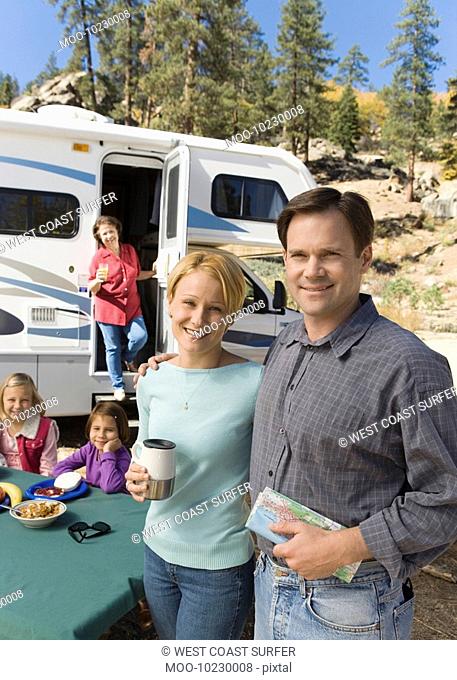 Couple and family outside RV in campground