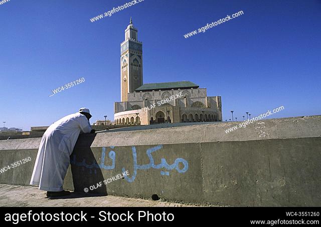 Casablanca, Morocco, Africa - A man stands at the shore in front of the Hassan II Mosque, the second largest mosque in Africa