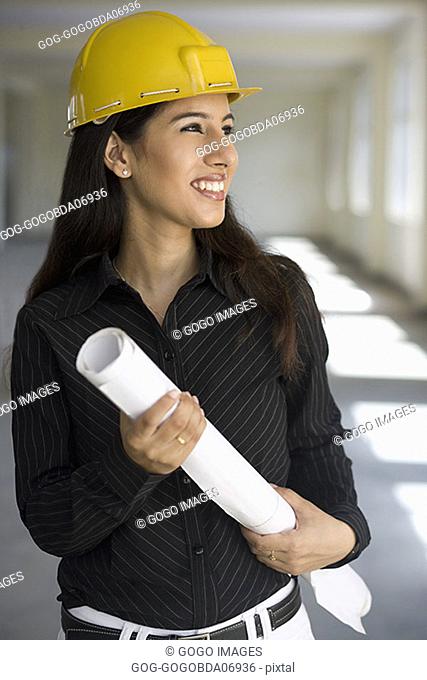 Businesswoman in a hard hat carrying blueprints