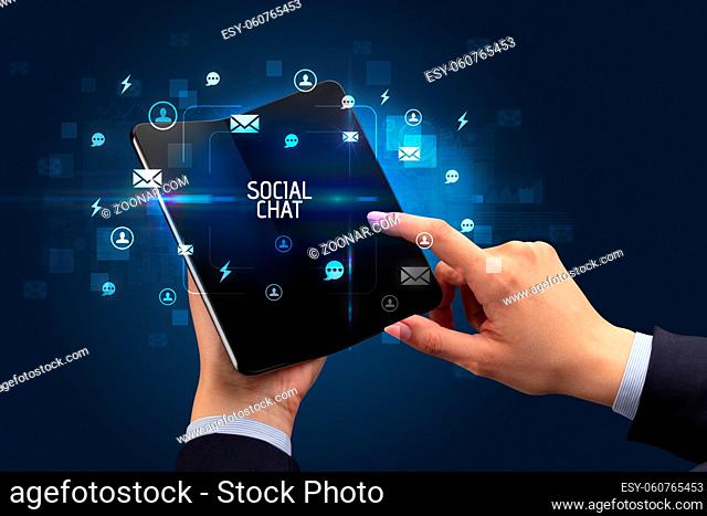 Businessman holding a foldable smartphone with SOCIAL CHAT inscription, social networking concept