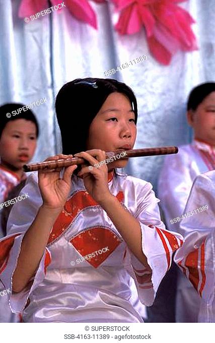 CHINA, SHANTOU, ELEMENTARY SCHOOL, GIRL STUDENT PLAYING FLUTE
