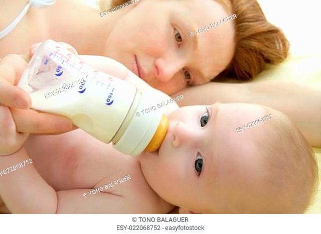 baby drinking bottle from mother hands