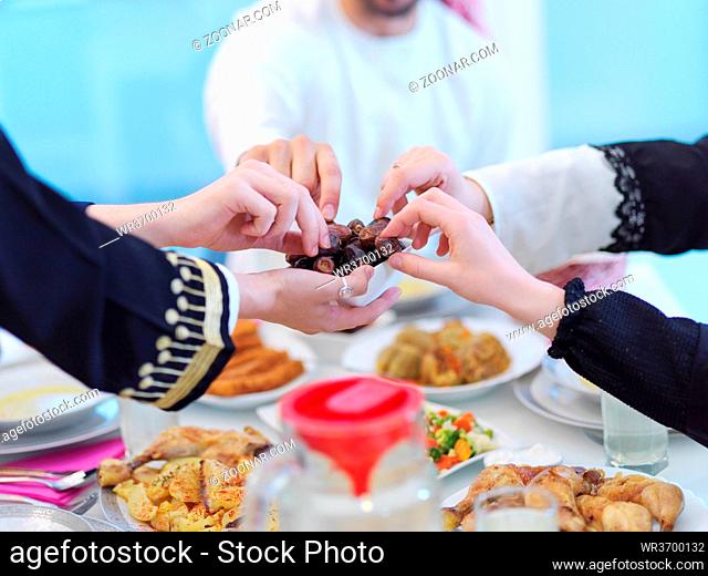 Eid Mubarak Muslim family having Iftar dinner eating dates to break feast. Eating traditional food during Ramadan feasting month at home