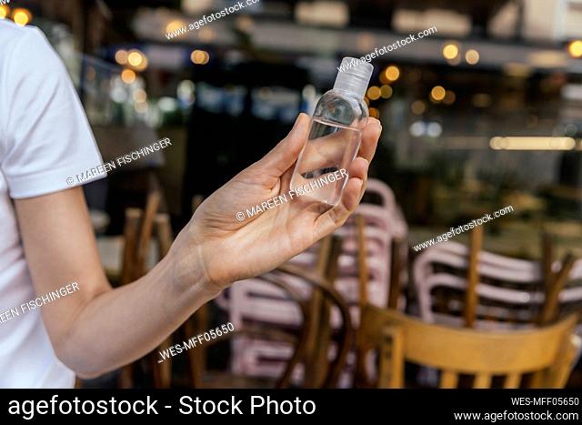Woman's hand holding flask with sanitizer