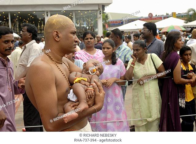 Pilgrim carrying his baby during the Hindu Thaipusam Festival from Sri Subramaniyar Swami Temple 272 steps up to Batu Caves, Selangor, Malaysia, Southeast Asia